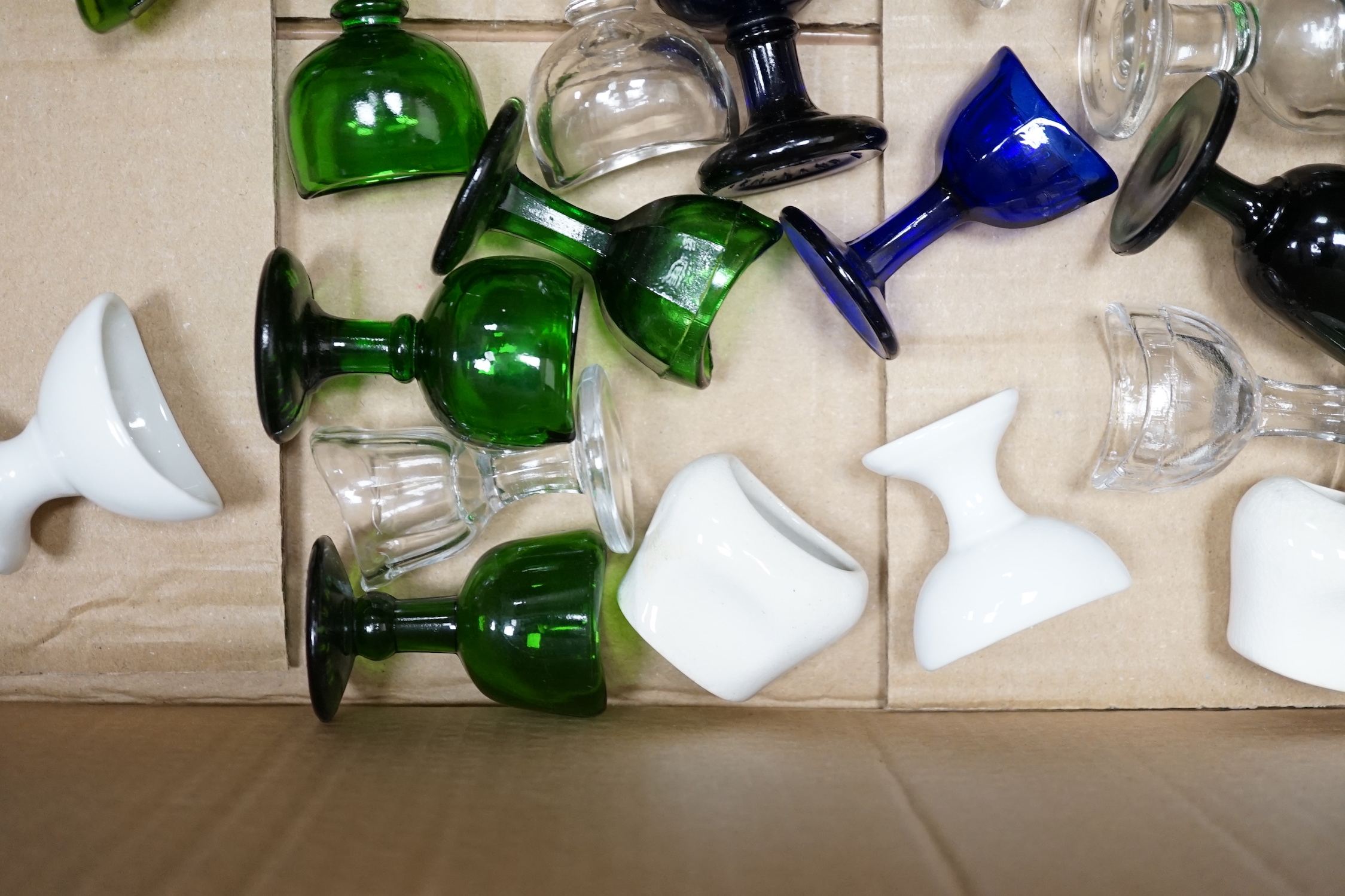 Thirty-four glass and porcelain eye baths, including green and blue glass examples